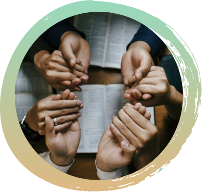 Four sets of hands on top of a wooden table. Each hand is holding the hand of the person next to them