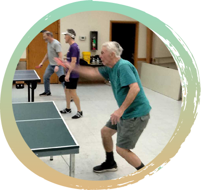 Man in green shirt and grey shorts playing Ping Pong