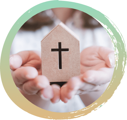 Hands holding a home shaped box with a pointed roof, in the center there is a cross